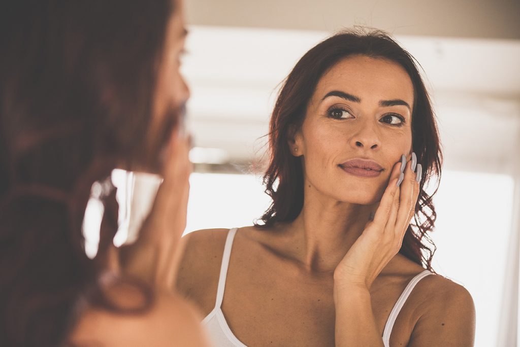 middle aged woman with smooth skin touching her face