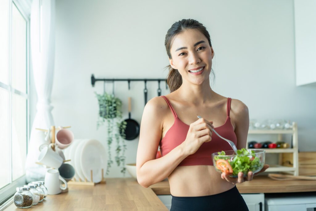 Young woman eating healthy salad full of superfoods that support beautiful, healthy skin